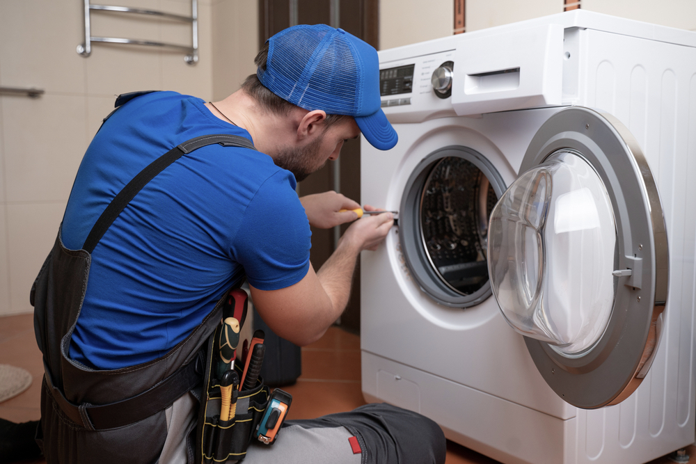 Working Man Plumber Repairs A Washing Machine In Home Washing