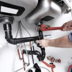 Hands Of Professional Plumber With A Wrench Clogged Sink