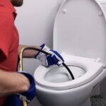plumber unclogging blocked toilet with hydro jetting