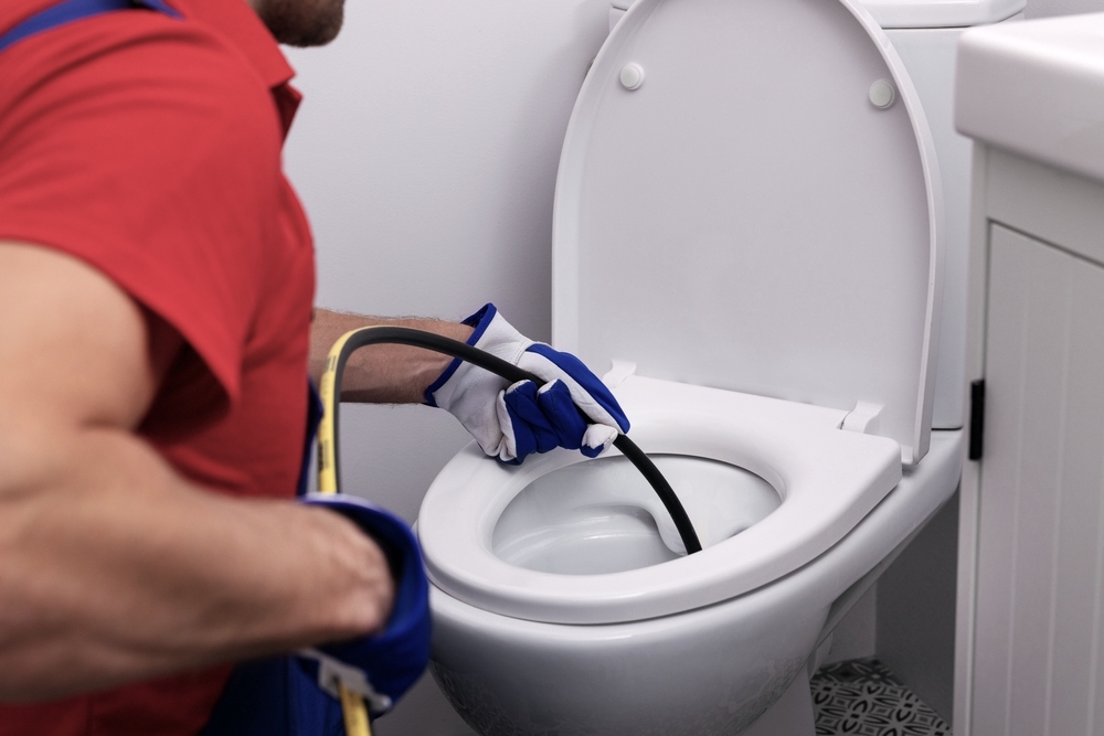 plumber unclogging blocked toilet with hydro jetting