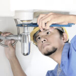 plumber repairing sink in restroom
