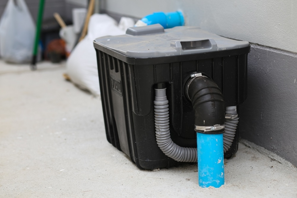 A black grease trap outside a commercial kitchen