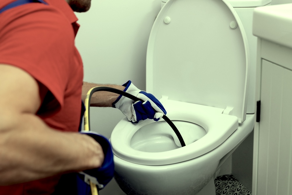 A plumber performs hydro jetting on a toilet bowl