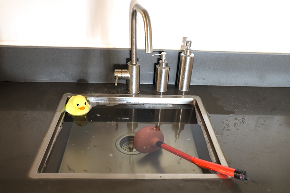 An overflowing sink with a rubber ducky