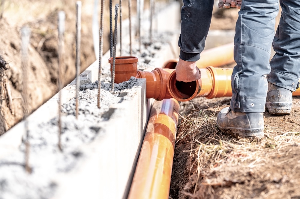 Plumber fixing orange pipes during a new construction of a house