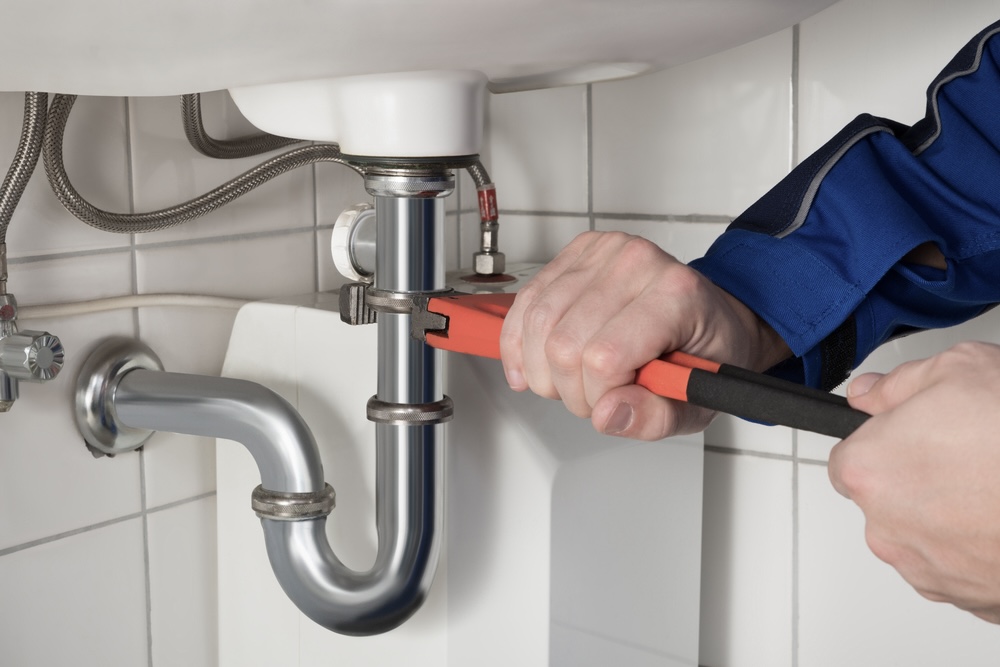 Closeup of a plumber’s hands fixing pipes and doing plumbing maintenance